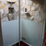 Glass enclosed shower surrounded by moat and rock waterfall
